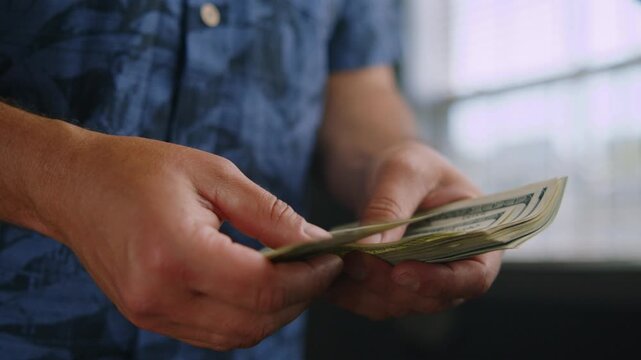 Hands skillfully sort through crisp bills in a charming cafe, sunlight streaming through the windows, creating a warm and inviting atmosphere for the onlooker
