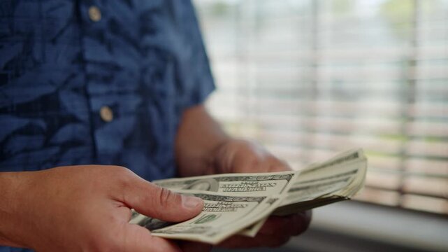 Hands sift through crisp dollar bills, absorbing the thrill of currency while sunlight dances through the window, creating a warm atmosphere