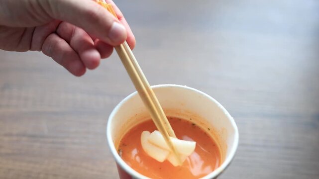 Close-up of spicy Korean tteokbokki rice cakes in a cardboard takeout box