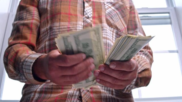 A man carefully counts his dollar bills, assessing how much money he has for the upcoming home repair project, planning necessary material expenses