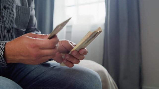 In a softly lit room, a man carefully counts Canadian dollars, his hands moving with precision and intent as he manages his finances in a peaceful setting