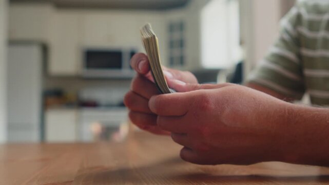 Hands gently count crisp bills in a cheerful kitchen setting, sunlight illuminating the scene as each note is handled with care and attention