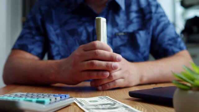 Hands gently hold a stack of cash in a cozy workspace, surrounded by a calculator and notes. Bright sunlight filters in, inspiring thoughts of financial success