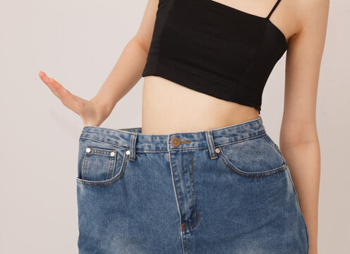Slim female waist in jeans and black top isolated on neutral background. Fashion and body shape concept