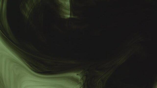 Abstract background of dark green and black ink swirling underwater. Mesmerizing fluid motion creates a moody, smoky organic pattern. Perfect for dramatic overlays.
