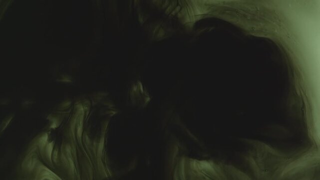 Abstract background of dark green and black ink swirling underwater. Mesmerizing fluid motion creates a moody, smoky organic pattern. Perfect for dramatic overlays.