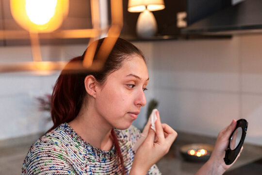 Young woman cleansing her face with a cotton pad before applying Halloween makeup