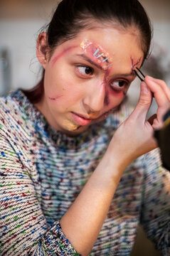 Redhead applying mascara over a stapled brow wound during Halloween makeup
