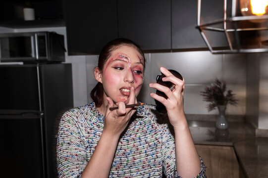 Costumed character applying makeup to her chin under harsh direct flash at night