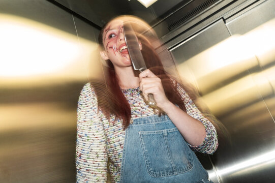 Menacing doll character in denim overalls wielding a knife inside an elevator