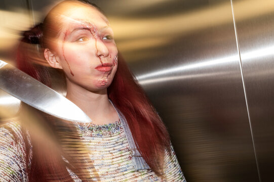 Deranged costumed character swinging a knife with motion blur in an elevator