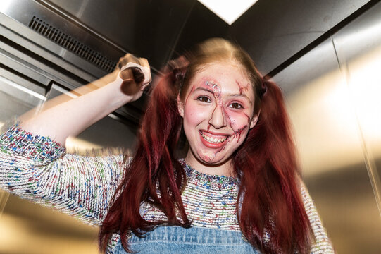 Grinning killer doll character raising a knife with red pigtails in an elevator