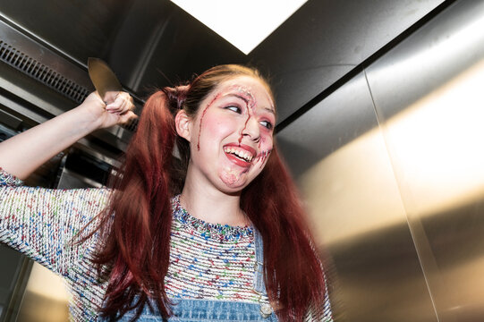 Laughing possessed character brandishing a knife under direct flash in an elevator