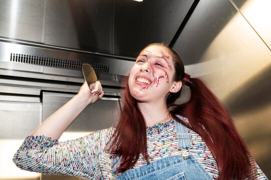 Unhinged doll character laughing with a raised knife in a metallic elevator