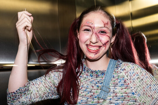 Deranged doll character tugging a red pigtail under stark flash in an elevator