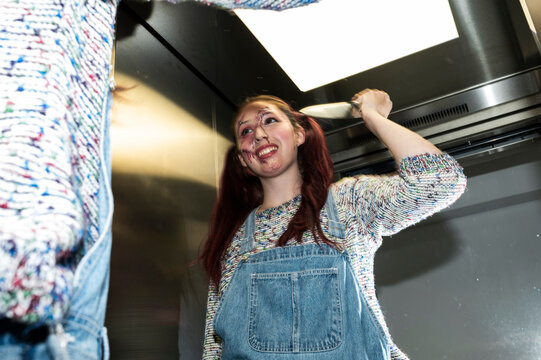 Menacing costumed character raising a knife overhead under flash in an elevator