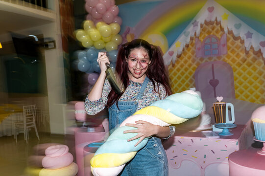 Deranged doll character clutching a plush toy in a kitschy candy themed studio