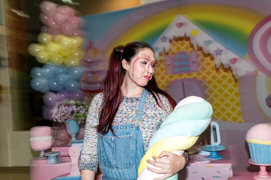 Sinister bloodied character holding a plush toy against a pastel candy land backdrop
