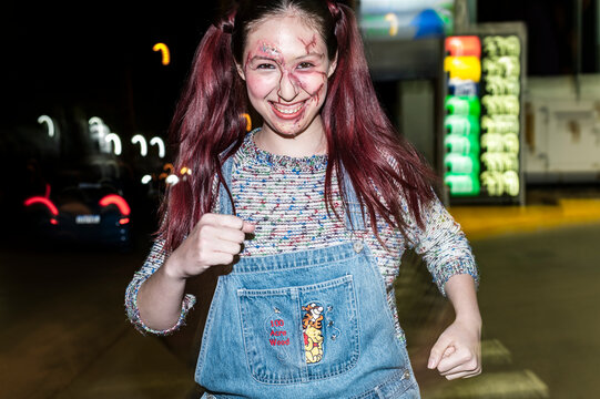 Costumed killer doll character raising a fist on a dark city street at night