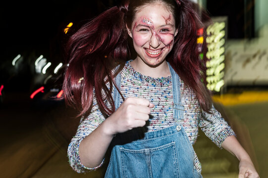Deranged character running with flying pigtails under direct flash on a street
