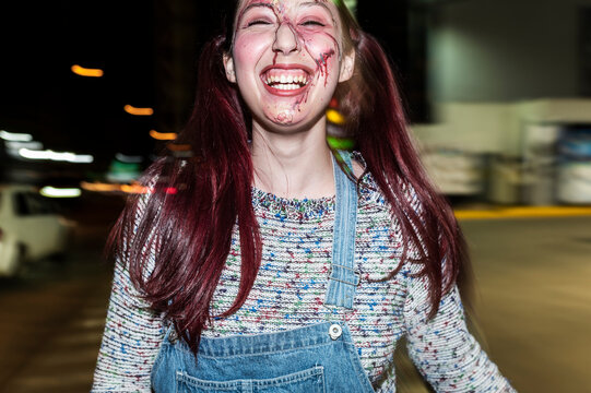 Laughing killer doll character with whipping hair under flash on a night street
