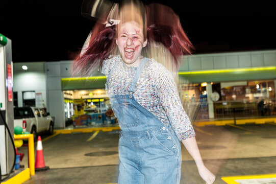 Deranged doll character flipping her hair under direct flash on a night street