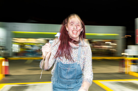 Grinning killer doll character holding a knife under direct flash at a gas station