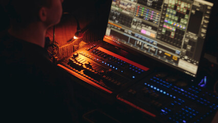 Naklejka na ściany i meble Lighting engineer operator working on mixing console workplace during live event concert on stage show broadcast, light mixer controller panel, sound technician workplace with professional equipment