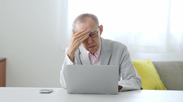 困った表情でパソコンを使う高齢者の男性