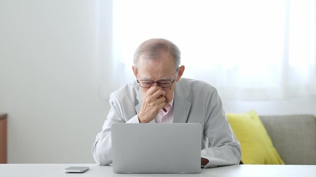 困った表情でパソコンを使う高齢者の男性