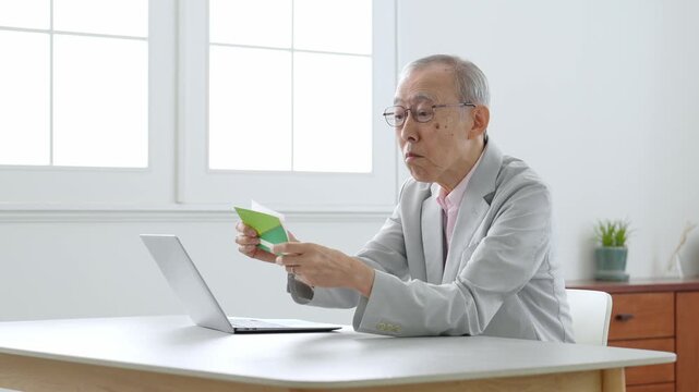 通帳を確認する高齢者の男性　インフレ　物価高　生活苦