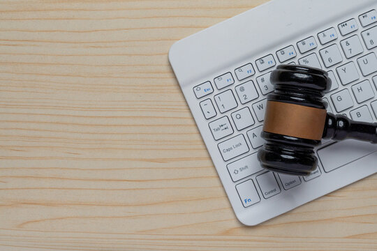 A wooden gavel on a white computer keyboard. Cyber law, digital regulations, internet crime, online auctions, and e-commerce legislation concept. Copy space for text.