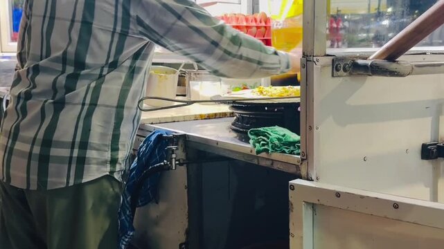 A street vendor selling martabak and terang bulan, typical Indonesian food, is cooking and serving customers at night.