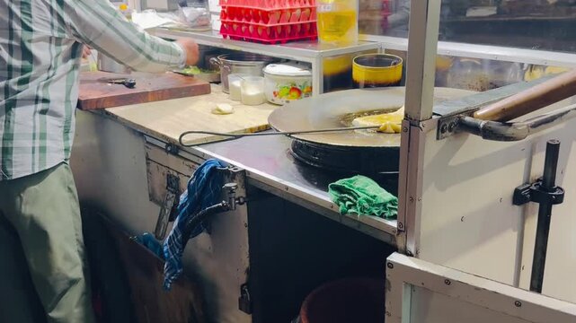 A street vendor selling martabak and terang bulan, typical Indonesian food, is cooking and serving customers at night.
