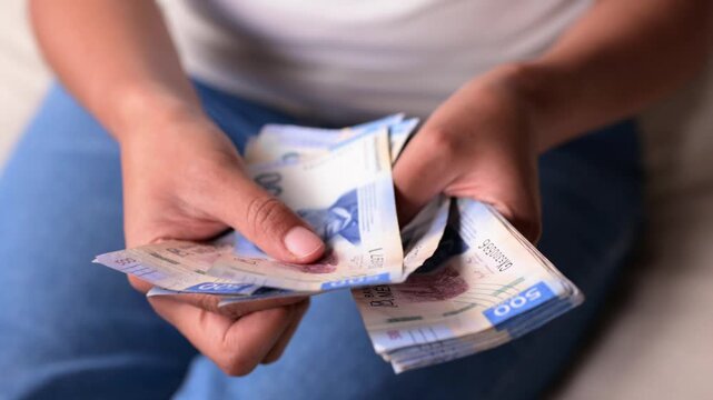 Close-up of a woman's hands counting cash, Mexican pesos