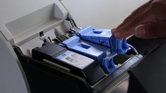 Hand inserting a new black ink cartridge into an inkjet printer