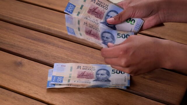 Woman's hands manually counting a stack of Mexican currency
