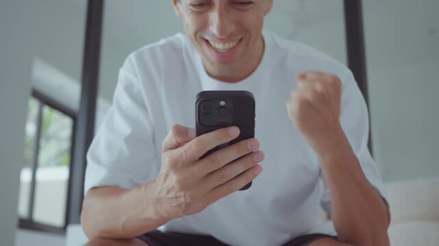 success man using smartphone celebrating online payment or financial result at home office. success concept with digital banking positive emotions and fintech achievement in modern lifestyle