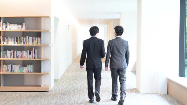 若手社員と上司が会話しながら歩くビジネスシーンの動画　顔無しの後姿