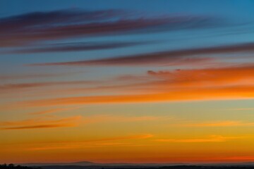 Fototapeta premium Vibrant Sunset Sky with Orange and Blue Streaks Across the Horizon