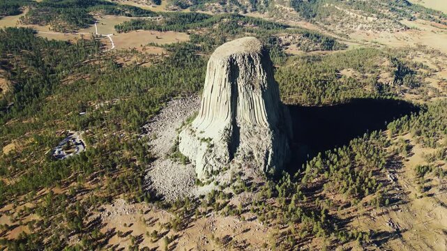 Devils tower aerial view during sunrise shows geological formation within wyoming mountain landscape.