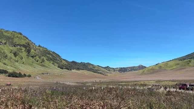 Beautiful landscape of green savanna hills near Mount Bromo under clear blue sky in East Java, Indonesia