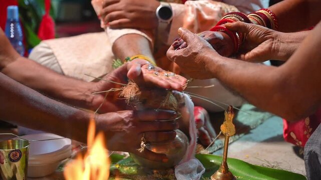 Close-up footage of bride and groom hands participating in traditional Hindu wedding rituals during a marriage ceremony in India. The scene captures sacred customs, ceremonial offerings