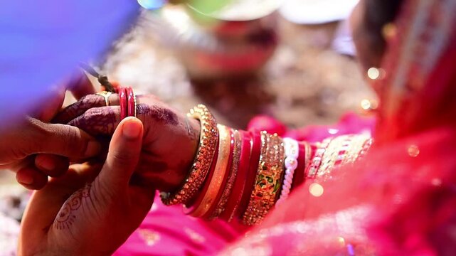 Close-up footage of bride and groom hands participating in traditional Hindu wedding rituals during a marriage ceremony in India. The scene captures sacred customs, ceremonial offerings