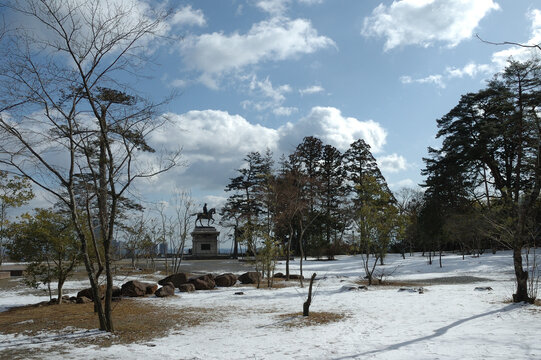 Snowy landscape of Sendai Castle ruins with the bronze statue of Date Masamune under a blue sky, Miyagi, Japan