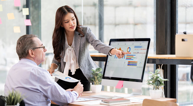 Asian businesswoman presenting financial data chart to senior colleague.