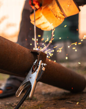Grounding clamp connected to steel pipe highlights essential role of electrical conductivity in welding operations. Industrial detail focused on safety, efficiency and stable fabrication results.