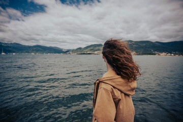 Naklejka premium Moody and atmospheric portrait of a woman by the sea bay on a breezy day.