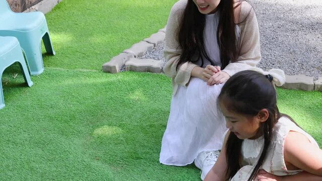 Young Girl and Mother Feeding Pet Rabbits at an Outdoor Animal Farm
