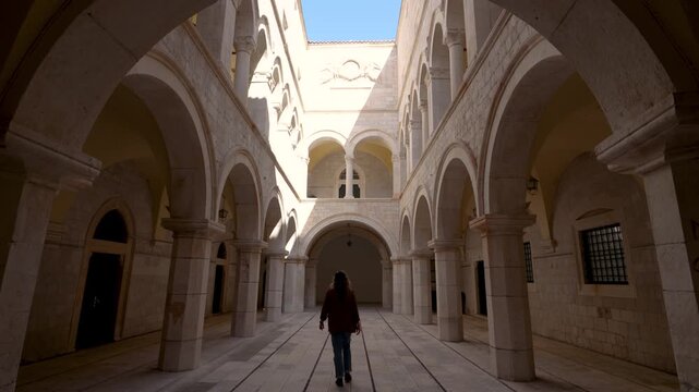 Dubrovnik Croatia Girl Walks Into Beautiful Church Temple Digital Nomad Solo Female Travel. Stone Archways Outdoor Courtyard Epic Location.